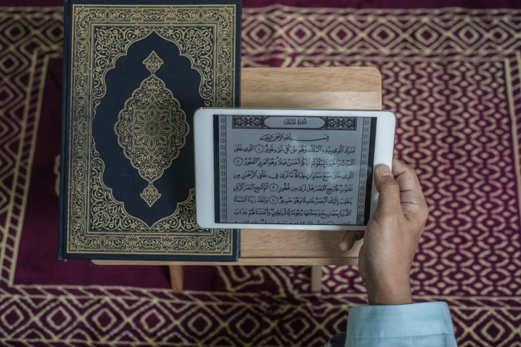 Asian Muslim man reading digital Al-Quran using tablet at home during Ramadan