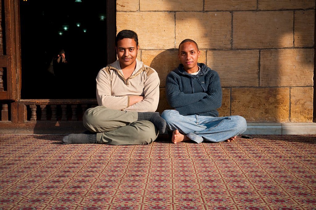 Cairo, Egypt - March 25, 2010: Two Muslim friends sit on the carpet at Al Azhar Mosque in Cairo, Egypt.