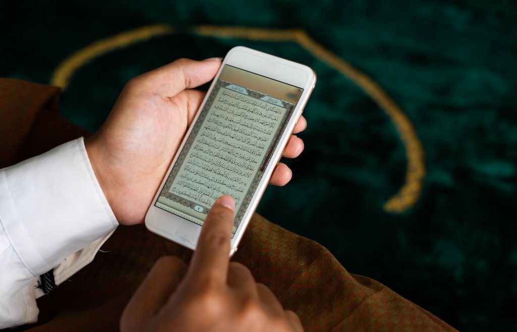 person holding a Quran digital in smartphone